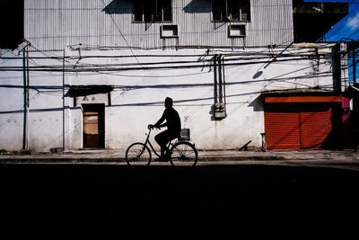 Side view of silhouette man riding bicycle on street