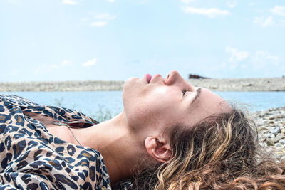 Man lying down on beach against sky