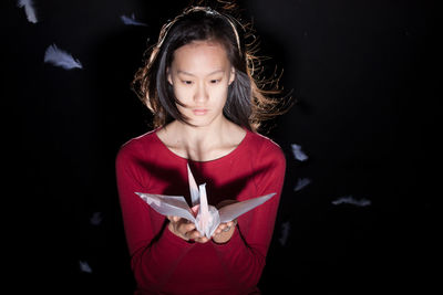 Portrait of a smiling girl holding paper against black background