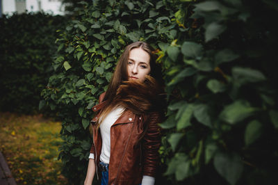 Portrait of young woman standing against plants