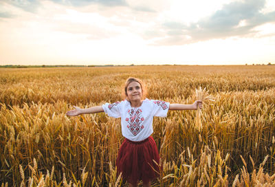 Girl holding wheat crop standing at farm