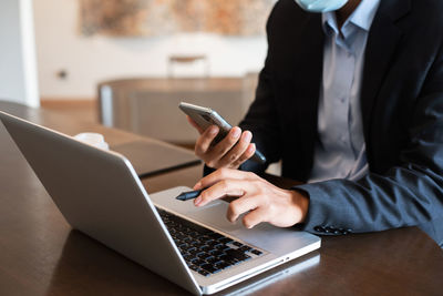 Midsection of man using laptop on table