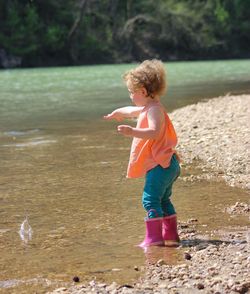 Side view of girl throwing stone in river
