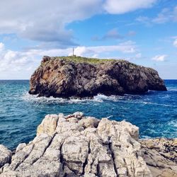 Rock formations by sea against sky