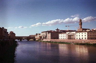 Buildings at waterfront against cloudy sky
