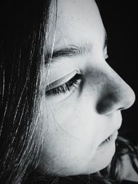 Close-up portrait of serious young woman against black background