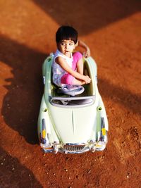 High angle view of cute girl sitting in toy car outdoors
