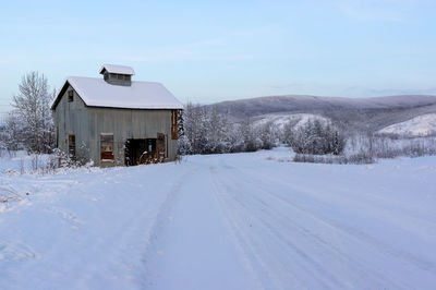 Snow covered land and buildings against sky