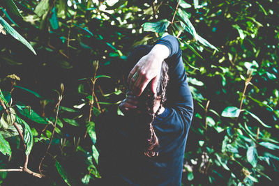 Rear view of woman with hand in hair against trees