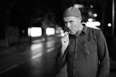 Man standing by illuminated light at night