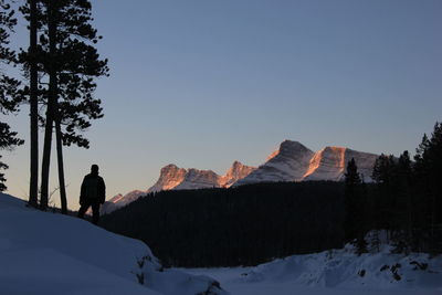 Rear view of silhouette man standing on mountain against clear sky