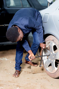 Young mechanic removing the wheel of a car in a workshop.