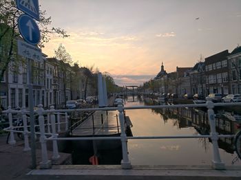 Buildings by river against sky during sunset