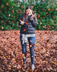 Young woman playing with autumn leaves at park