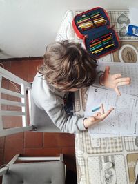 High angle view of boy reading book on table