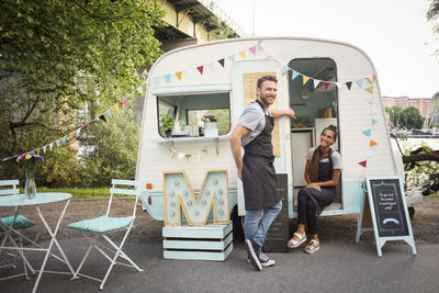 Portrait of happy male owner with female colleague outside food truck on street