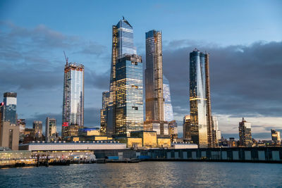 Sea by modern buildings against sky in city