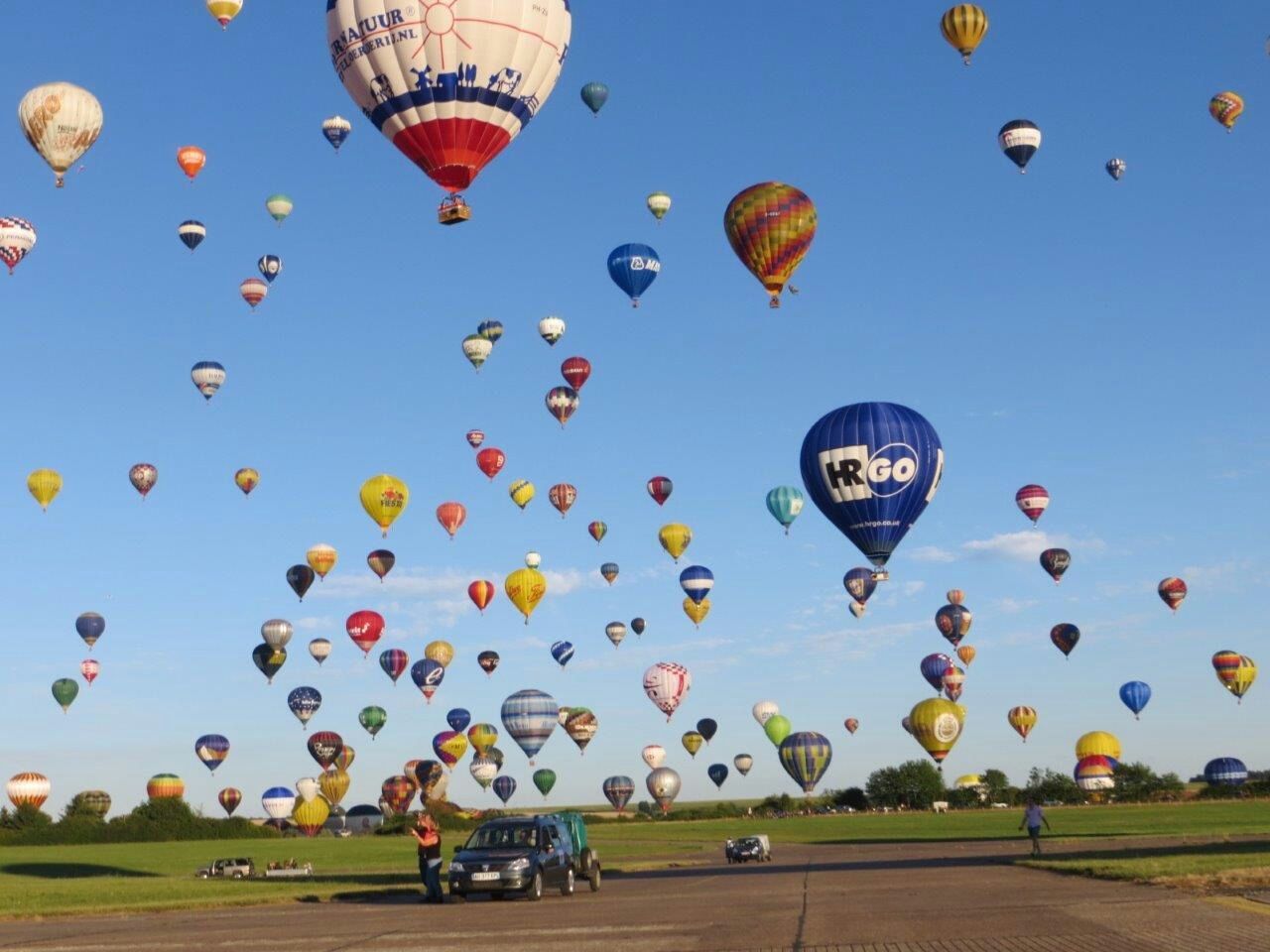 mid-air, flying, leisure activity, hot air balloon, fun, parachute, transportation, sport, sky, lifestyles, large group of people, blue, enjoyment, multi colored, grass, clear sky, extreme sports, field, adventure