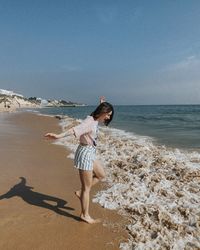 Happy girl playing with waves on the beach