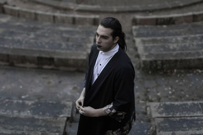 Young man looking away while standing on steps 