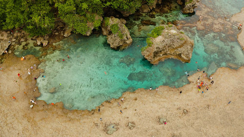Natural pools on the rocky shore with tourists formed at low tide. magpupungko natural rock pools.