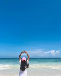 Rear view of man standing at beach against sky