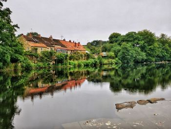 Scenic view of lake by buildings against sky