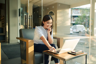 Woman using phone while sitting on table