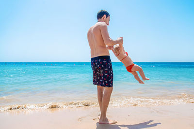 Full length of father playing with daughter on beach
