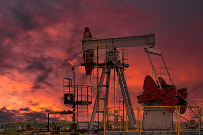 Scenic view of oil drill rig  against sky during sunset