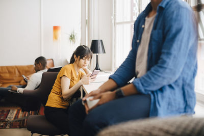 Female programmer using mobile phone on desk while sitting in office