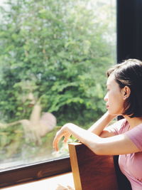 Young woman looking through window