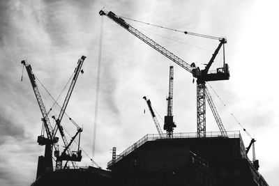 Low angle view of cranes against sky