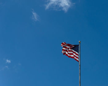 Low angle view of flag against blue sky