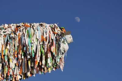 Low angle view of multi colored paper hanging against clear blue sky