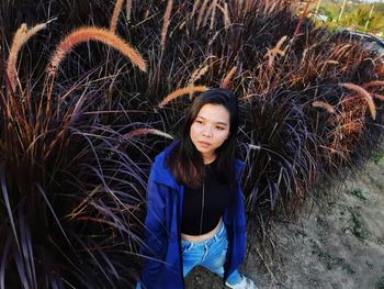 Portrait of young woman standing amidst plants