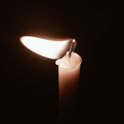 Close-up of candle burning in darkroom