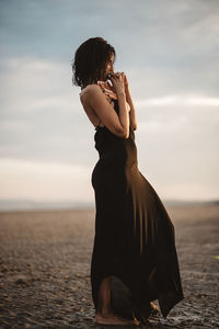Rear view of woman on beach against sky