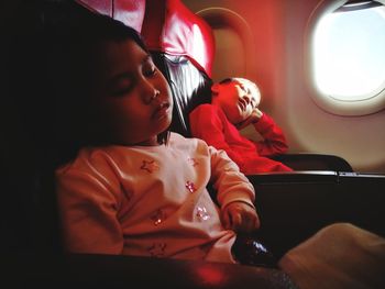 Children sleeping while sitting on vehicle seats in airplane