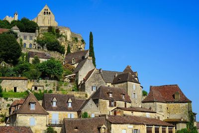 Low angle view of old village at top of hill against clear blue sky in dordogne, south of france