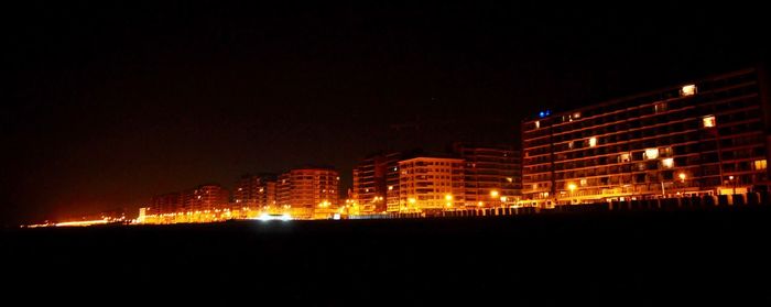 Illuminated cityscape against sky at night