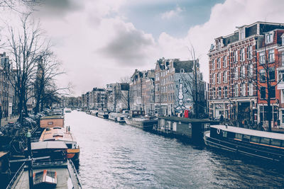 Canal in city against sky