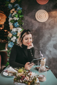 Young woman using mobile phone while standing on table