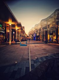Illuminated street amidst buildings against sky at night