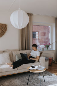 Woman using laptop on sofa  barefoot