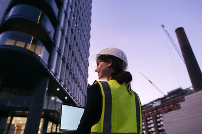 Engineer holding laptop at dusk