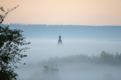 Only the church tower top looks out of the fog 