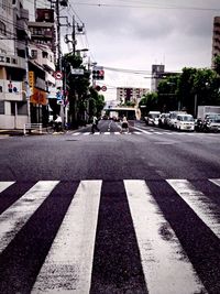 Road by street in city against sky