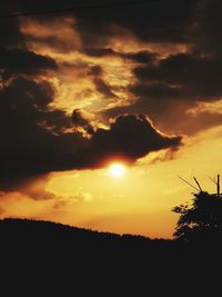 Silhouette landscape against dramatic sky during sunset