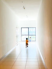 Rear view of man walking in corridor of building